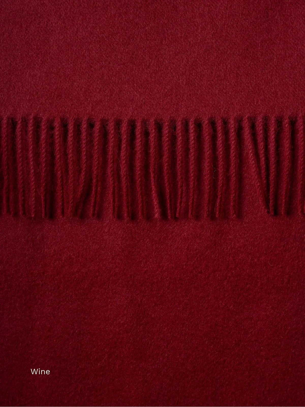 Wine red naturally dyed baby alpaca scarf, close-up of the deep burgundy fabric and fringe