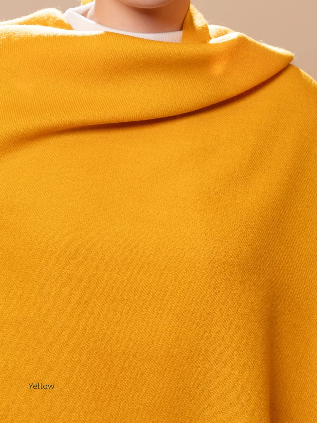 Yellow naturally dyed baby alpaca shawl wrapped around the shoulders, close-up of the soft Peruvian alpaca fabric