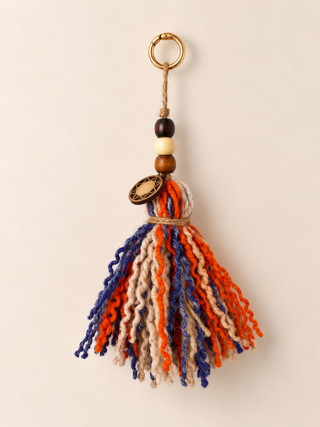 Beaded wool tassel with curly orange, blue and ivory strands, three wooden beads, a wooden Orange Inca sun charm and a light gold ring | Tasselita by Orange Inca