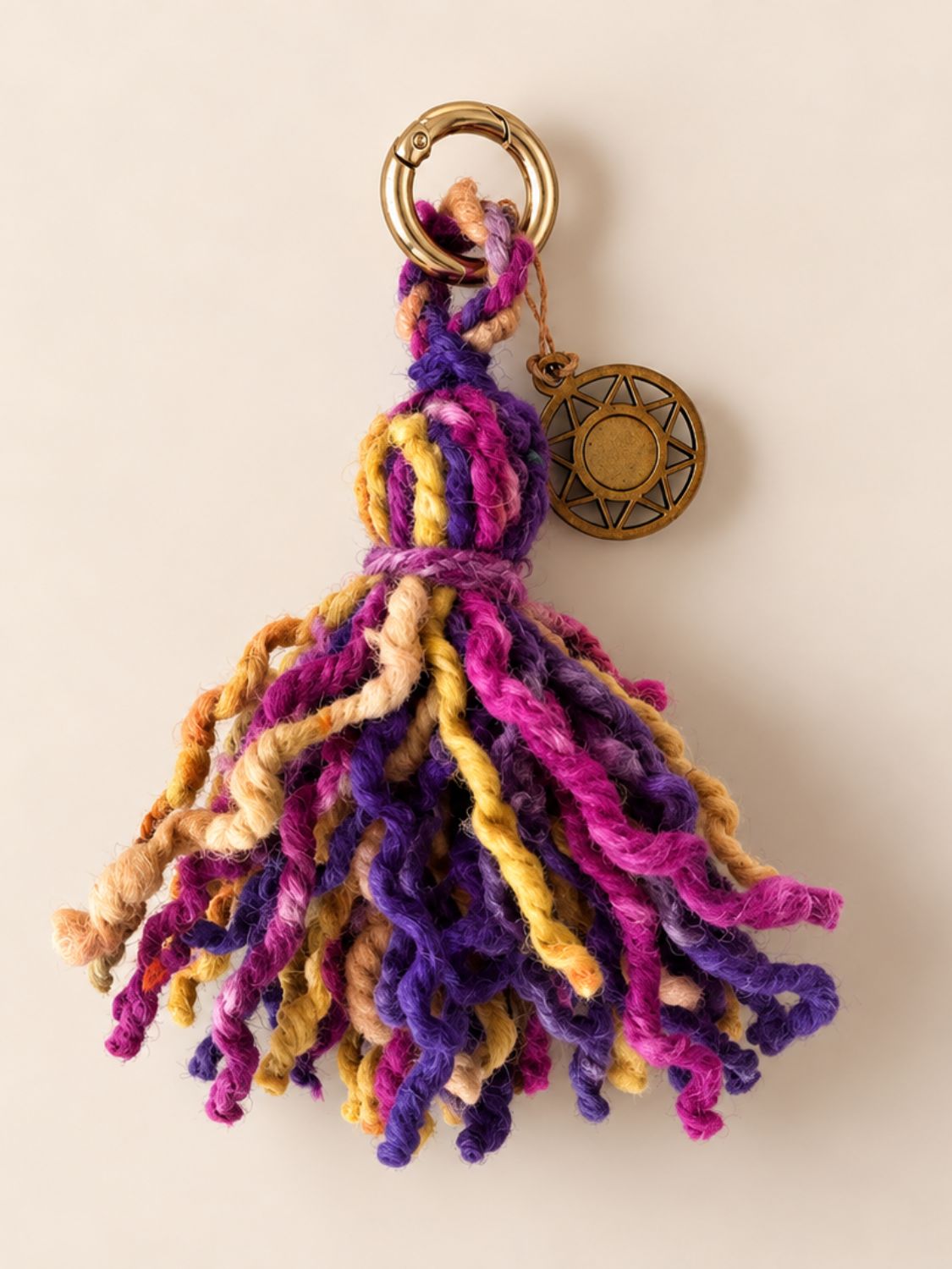 Mini wool tassel in washed fuchsia, purple and yellow with a light gold ring and a wooden Orange Inca sun charm | Tasselita by Orange Inca