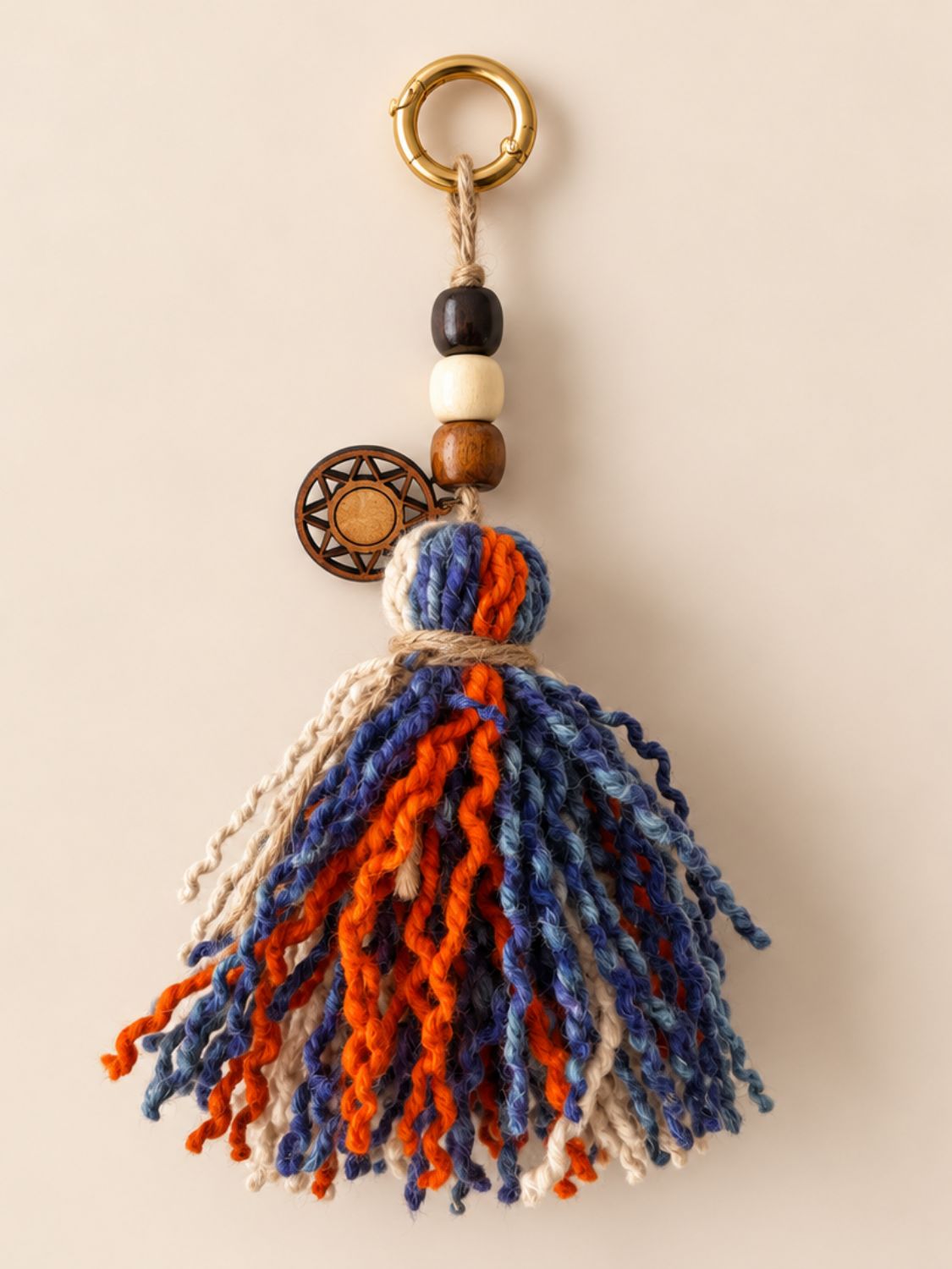 Beaded wool tassel with curly orange, blue and ivory strands, three wooden beads, a wooden Orange Inca sun charm and a light gold ring | Tasselita by Orange Inca