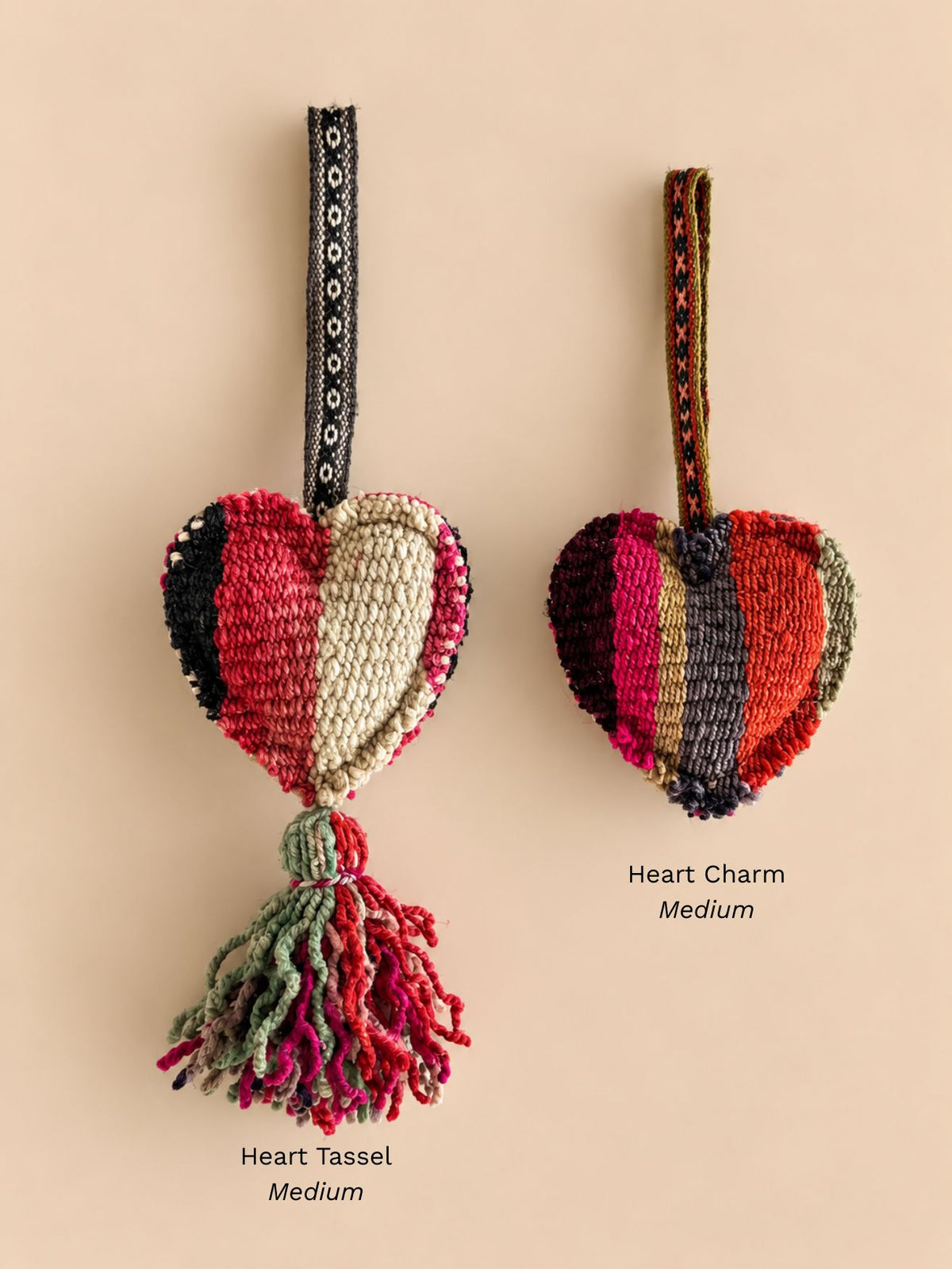 Medium heart wool tassel in red, cream and black with a green and red tassel next to a medium striped heart wool charm, labelled Heart Tassel Medium and Heart Charm Medium | Tasselita by Orange Inca