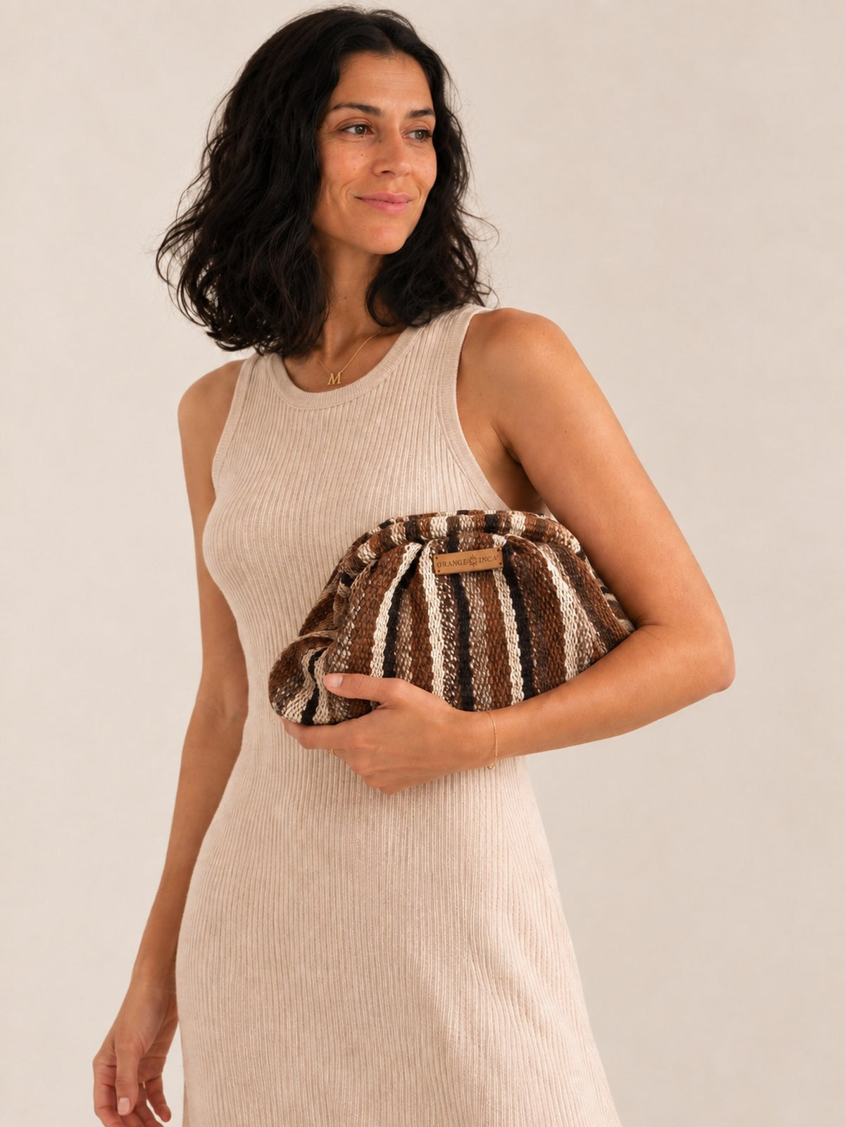 Woman in a ribbed knit dress holding the Luna kiss lock clutch in browns, black and ivory | Orange Inca