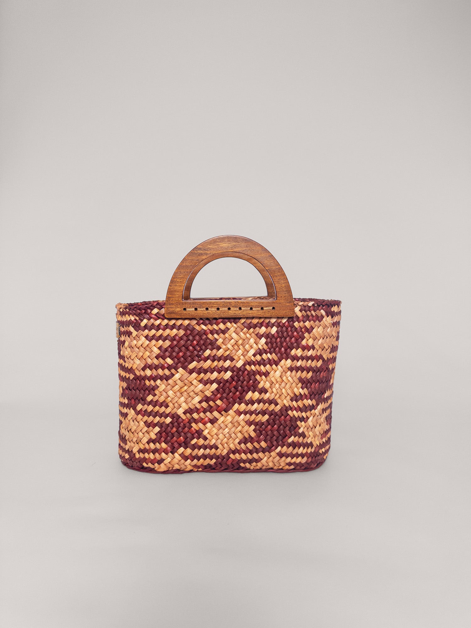 The Sophia bag in camel and beige, handwoven with a wooden handle, showcasing a colorful earthy design.