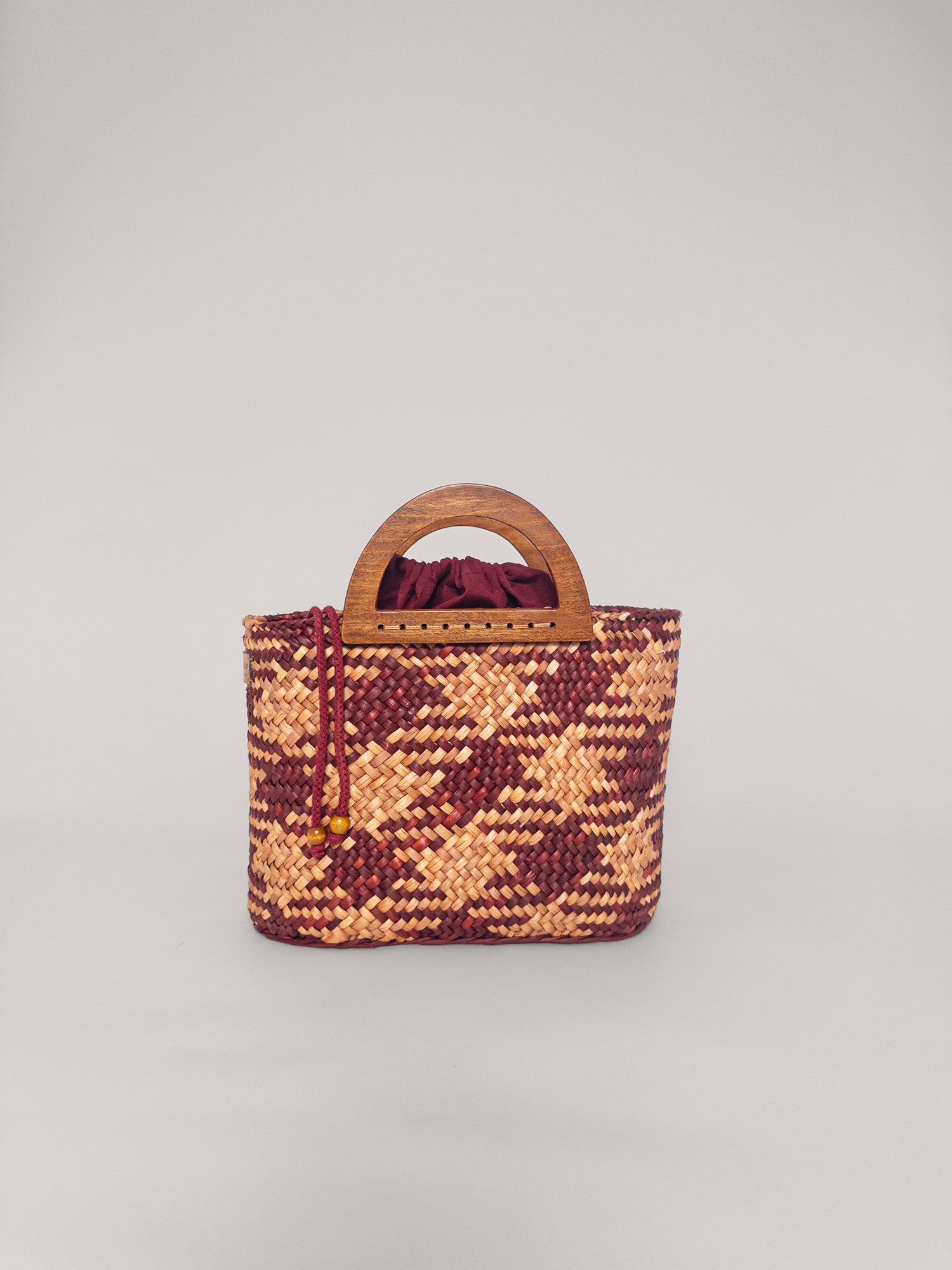 The Sophia bag in camel and beige, handwoven with natural dyes, featuring a wooden handle and drawstring closure.
