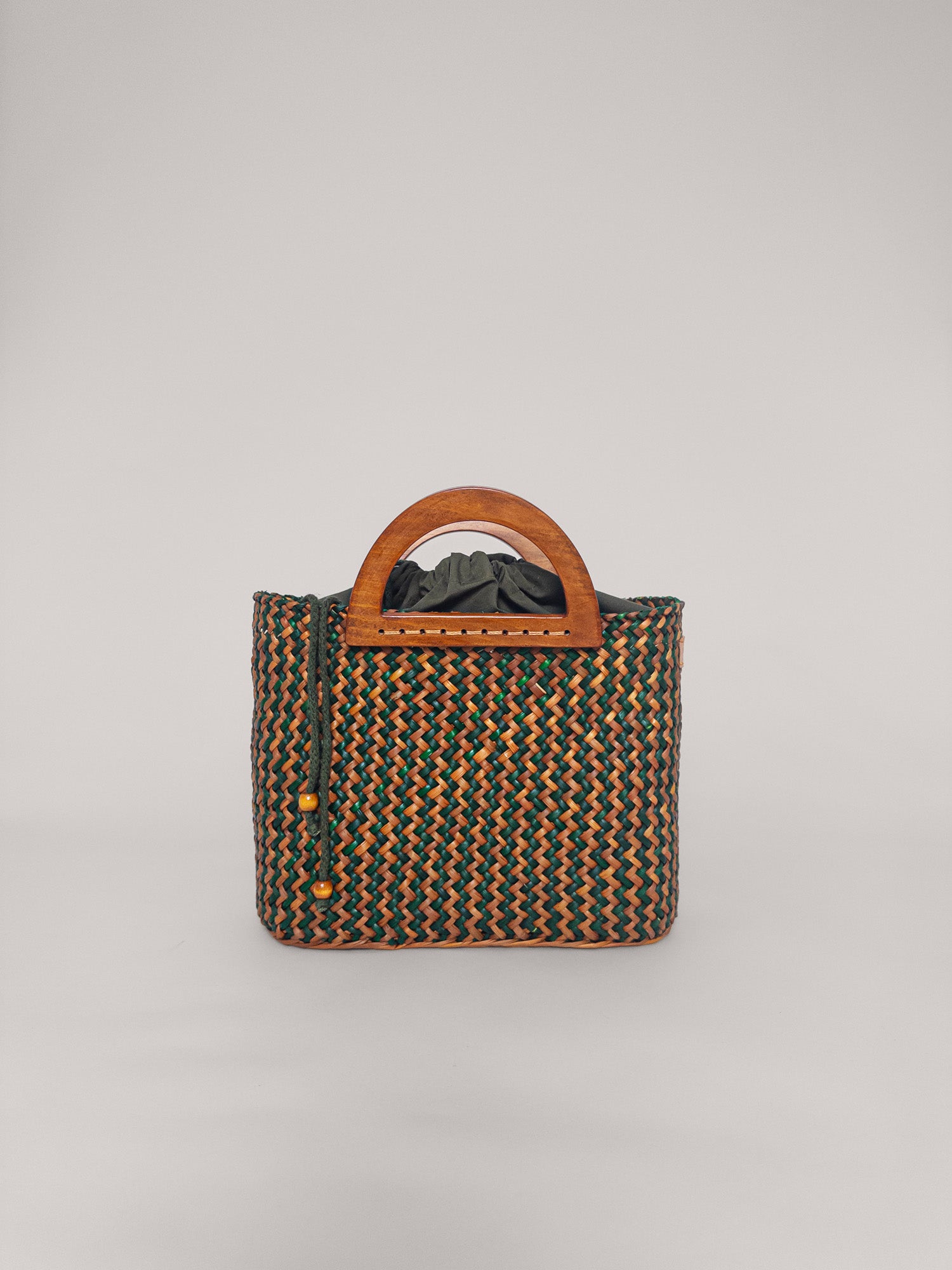 The Sophia bag in olive green and camel, handwoven with wooden handles and a spacious interior.