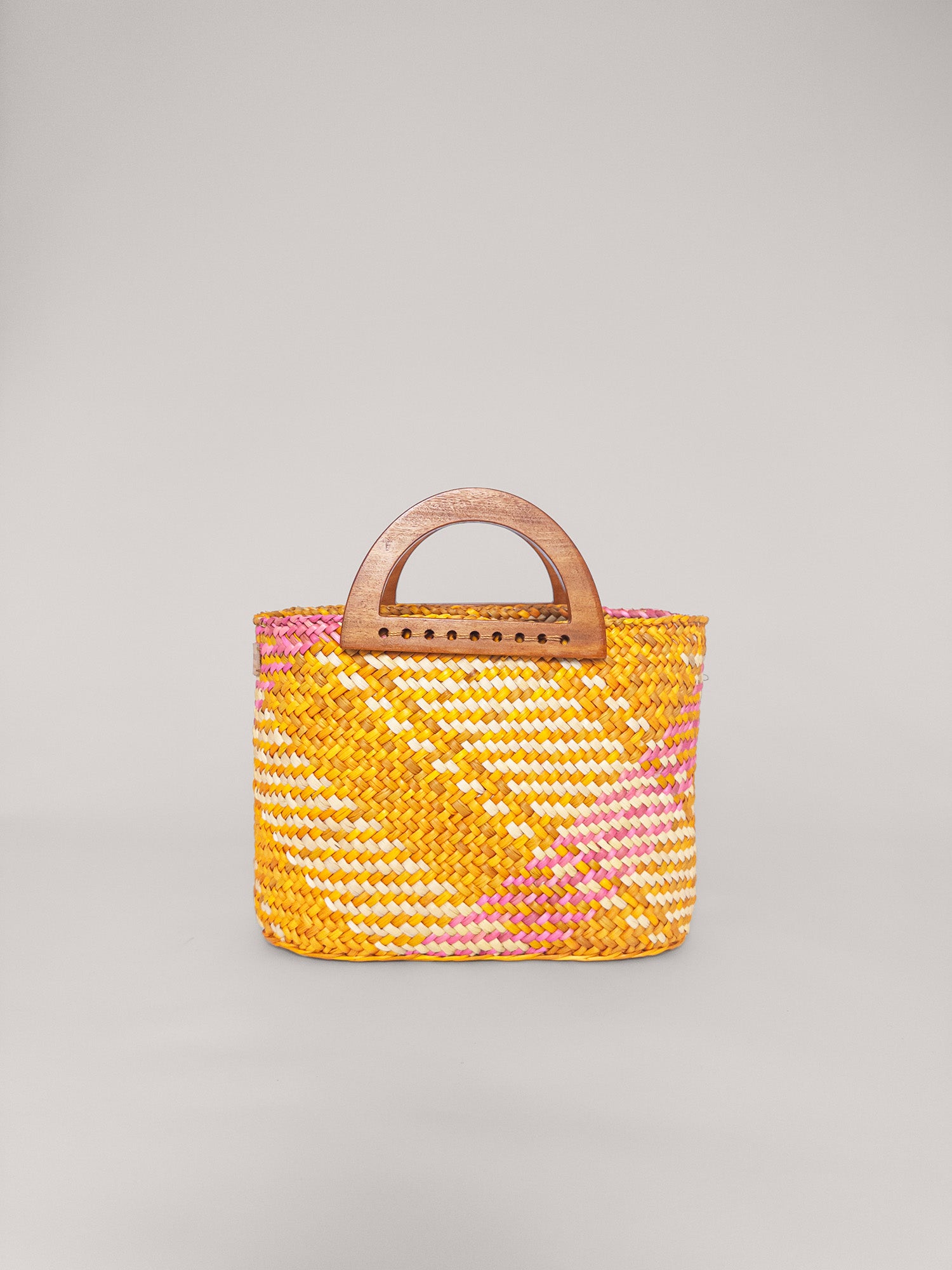 The Sophia handbag in washed yellow and pink, featuring handwoven design and wooden handles.