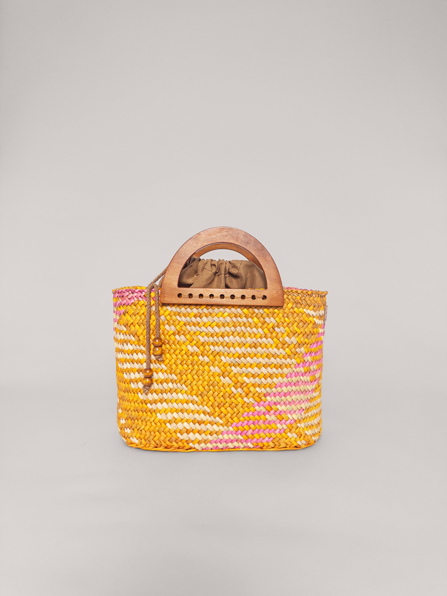 The Sophia handbag in washed yellow and pink, handwoven with wooden handles and cotton lining.